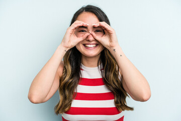Naklejka premium Young caucasian woman isolated on blue background showing okay sign over eyes