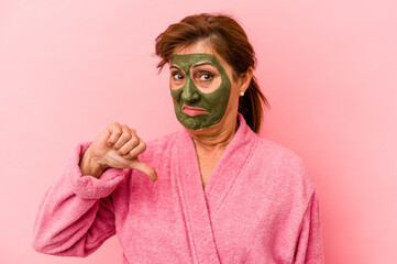 Middle age caucasian woman wearing a facial mask isolated on pink background showing a dislike gesture, thumbs down. Disagreement concept.