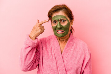 Middle age caucasian woman wearing a facial mask isolated on pink background showing a disappointment gesture with forefinger.