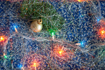 Golden ball with the branch of Christmas tree with a silver tinsel and colorful garland. Top view. New year background with a free space for text