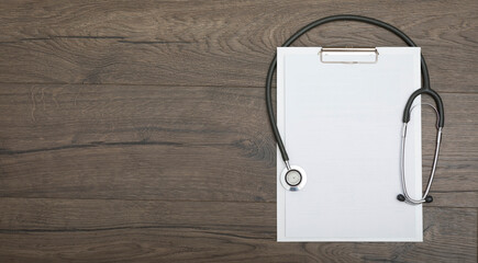 Top view on empty medical sheet and stethoscope on wooden table with copy space. Place for text and...