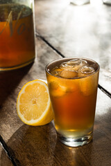 Cup of lemon ice tea, with a lemon half aside, on a wooden table