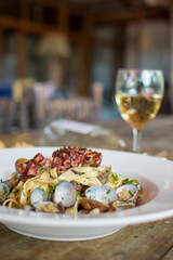Pasta with seafood. Prawns, squid and octopus. white plate olives.

