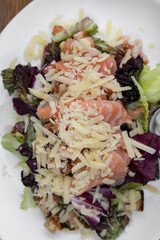 Caesar salad background. Top closeup view of a fresh Caesar salad with lettuce, parmesan cheese, bread croutons, salmon, bacon and Caesar dressing.