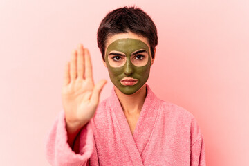 Young caucasian woman wearing a face mask isolated on pink background standing with outstretched hand showing stop sign, preventing you.