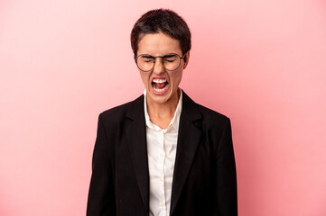 Young business woman isolated on pink background screaming very angry and aggressive.