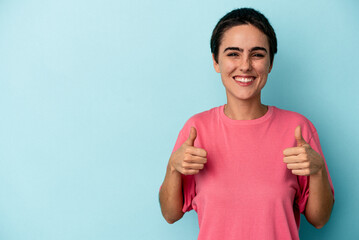 Young caucasian woman isolated on blue background smiling and raising thumb up