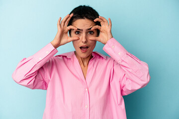 Young caucasian woman isolated on blue background keeping eyes opened to find a success opportunity.