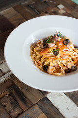 Pasta with seafood. Prawns, squid and octopus. white plate olives.

