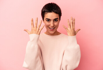 Young caucasian woman isolated on blue background showing number ten with hands.