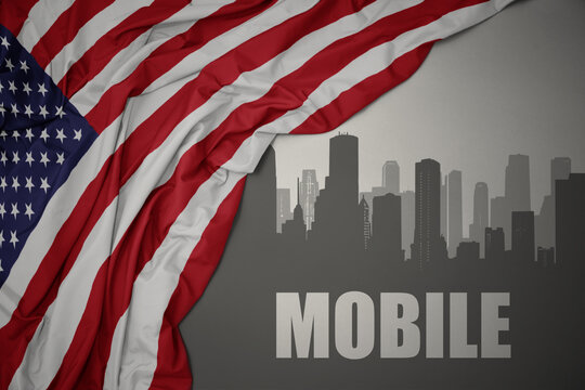 abstract silhouette of the city with text Mobile near waving national flag of united states of america on a gray background. 3D illustration