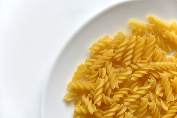 Yellow twisted raw pasta on a white plate