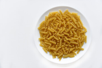 Yellow twisted raw pasta on a white plate