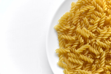 Yellow twisted raw pasta on a white plate