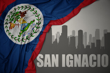 Fototapeta na wymiar abstract silhouette of the city with text San Ignacio near waving national flag of belize on a gray background. 3D illustration
