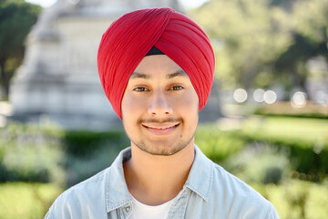Young handsome sikh guy in traditional head wrap turban looking at the camera and smiles, close-up portrait of serene happy Indian male student, entrepreneur standing outdoor