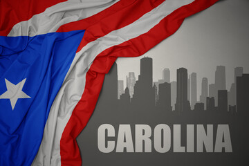 Fototapeta na wymiar abstract silhouette of the city with text Carolina near waving national flag of puerto rico on a gray background. 3D illustration