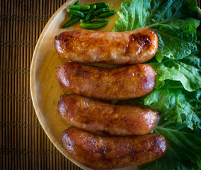 Isaan sausage or Thai Northeastern sausage , pork and rice sausages (Sai Krok Isan ) on wood plate with cabbage, and chilli - obrazy, fototapety, plakaty