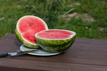 Watermelon cut in half on a table outside in the hot summer. - 515006550