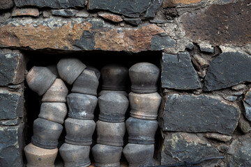 Clay pots stacked inside the wall cabin, Black rock stone wall background, pattern or texture