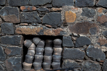Clay pots stacked inside the wall cabin, Black rock stone wall background, pattern or texture