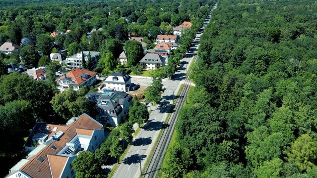 drone aerial view suburbs munich. luxury upper middle class housing in outskirts of bavarian capital in germany. Summer day green trees, cars driving on street, quiet city life.
