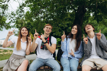 Group of student friends pointing up at copy space in park