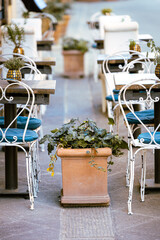 Tischreihe mit Blümenkübel an einem Restaurant in der Toskana
