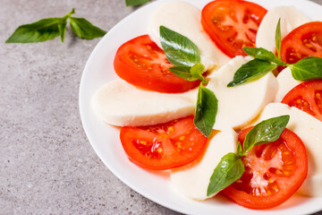 Close-up photo of caprese salad with ripe tomatoes, basil, buffalo mozzarella cheese. Italian and Mediterranean food concept. Fresh and healthy organic meal. Starter and antipasti. 