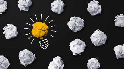 Good idea sign concept with paper light bulb isolated in black background. Crumpled paper ball with doodle hand drawing.