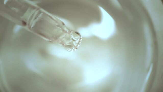 A drop of clear liquid from a pipette close-up