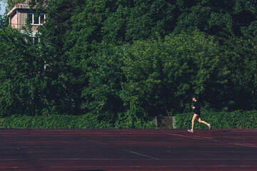 girl runs along the track at the stadium. cardio workout.