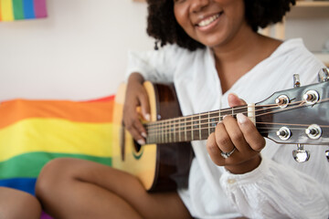 Beautiful Africa American woman playing acoustic guitar, cover for online courses, learning at home...