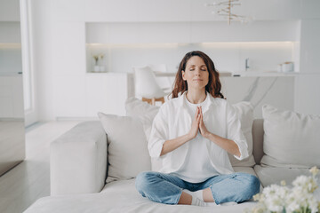 Serene young latin woman practicing yoga and posture exercise, lotus asana at home.