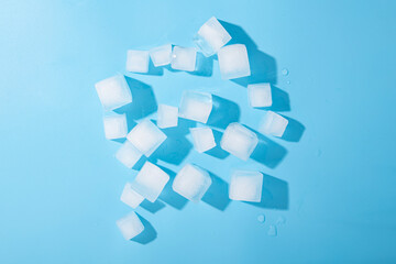 Many ice cubes on a blue background. Top view, flat lay