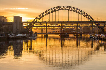 The Tyne Bridge in Newcastle at sunset, reflecting in the almost still River Tyne beneath