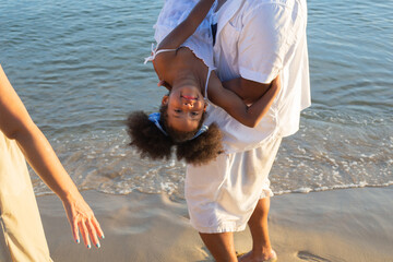 African American playful father carrying daughter at the beach. family enjoy playing together....