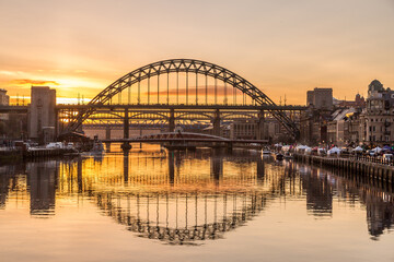 Fototapeta na wymiar The Tyne Bridge in Newcastle at sunset, reflecting in the almost still River Tyne beneath