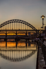 The Tyne Bridge in Newcastle at sunset, reflecting in the almost still River Tyne beneath