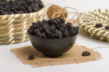 dried black grapes served in bowl isolated on napkin side view of dry fruits on grey background