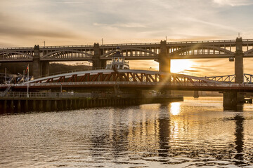 Obraz na płótnie Canvas The Tyne Bridge in Newcastle at sunset, reflecting in the almost still River Tyne beneath