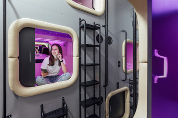 Young woman with gadgets in modern look capsule hotel