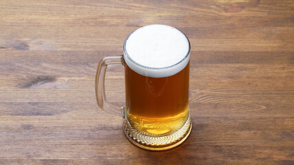 A large mug of light tasty cold beer on a wooden table, close-up, rustic style