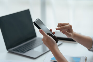 Asian businesswoman in formal suit in office happy and cheerful during using smartphone and working.