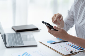 Asian businesswoman in formal suit in office happy and cheerful during using smartphone and working.