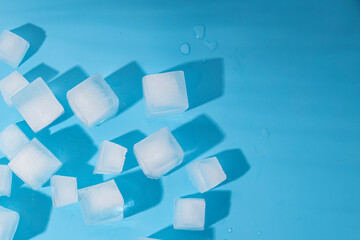 Many ice cubes on a blue background. Top view, flat lay