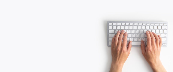 Female hands on the keyboard on a white background. Top view, flat lay. Banner - obrazy, fototapety, plakaty