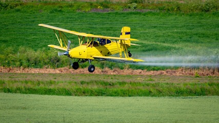 Crop duster plane sprays fertilizer on crops