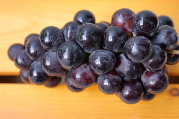 Clusters of ripe purple grapes in wooden background. 