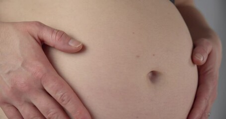 Woman running her hands over her pregnant belly. Macro close up, gimbal